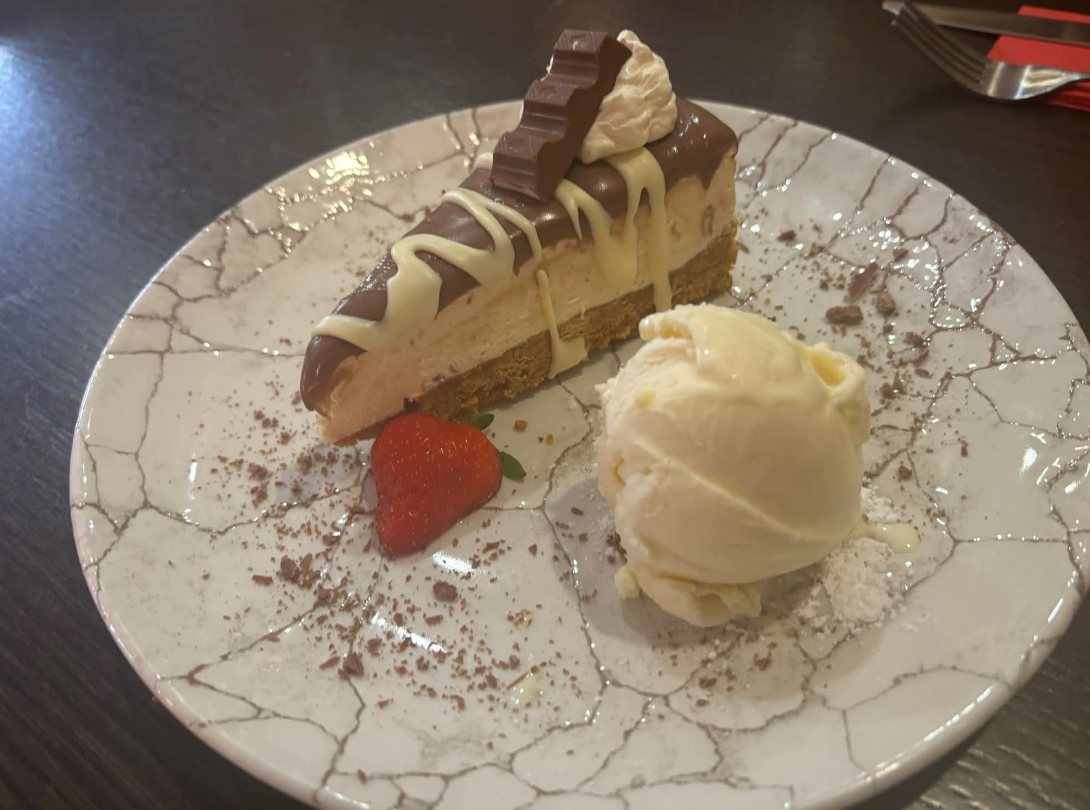 Cheesecake with chocolate, cream, a strawberry and vanilla ice cream